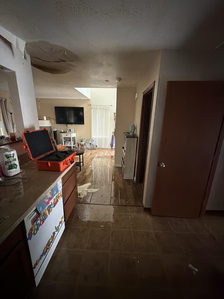 Standing water across the floor of a flooded home with a collapsed ceiling